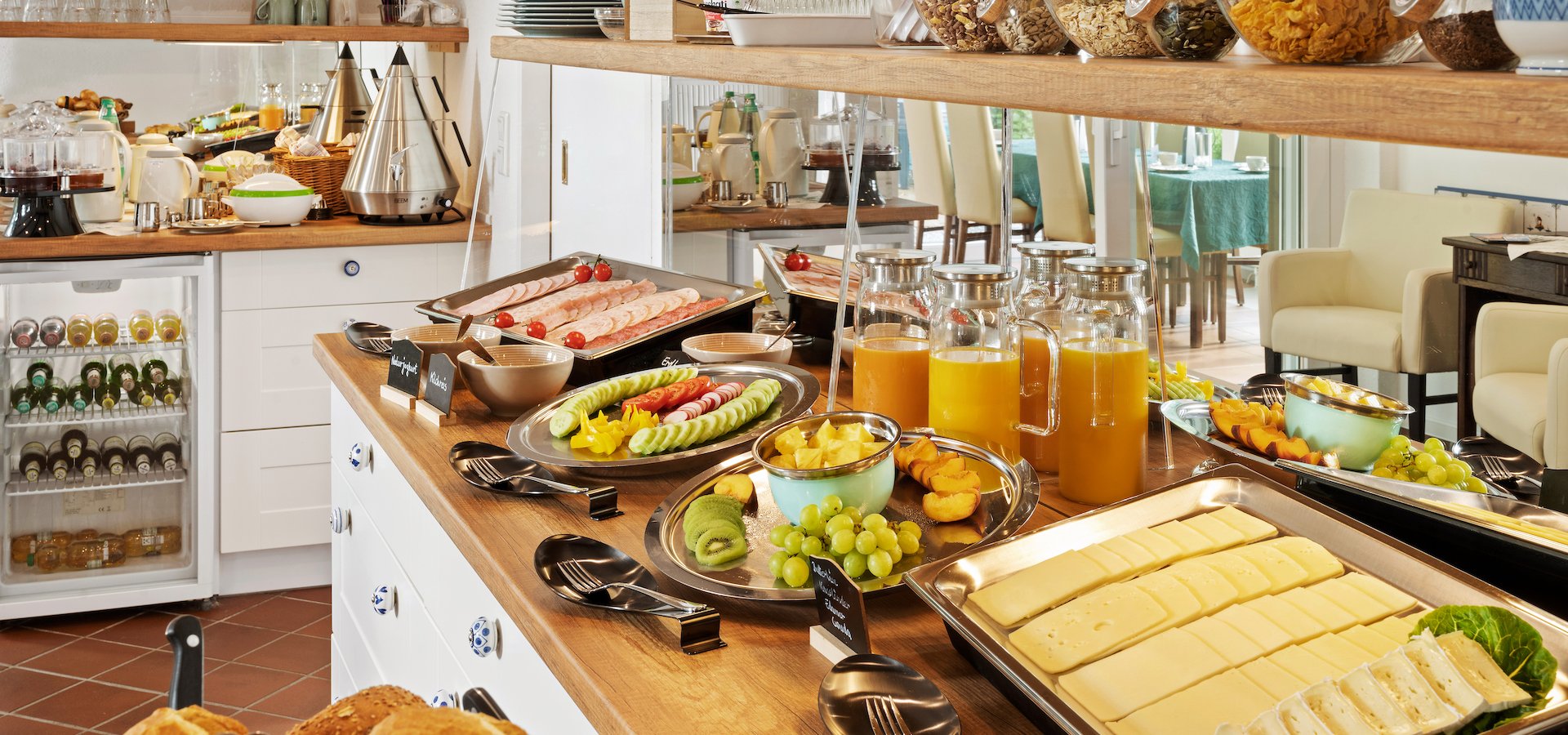 Frühstücksbuffet mit Käse, Obst, Aufschnitt, frischen Brötchen und einer Auswahl an Müsli und Cornflakes