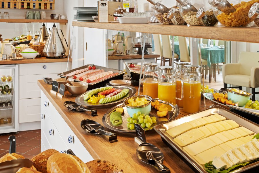 Frühstücksbuffet mit Käse, Obst, Aufschnitt, frischen Brötchen und einer Auswahl an Müsli und Cornflakes