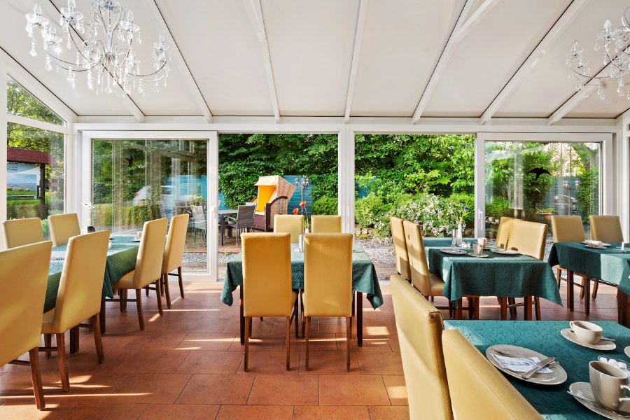 Gedeckte Tische im Wintergarten des Hotels